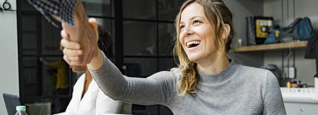 woman in office smiling and shaking hands