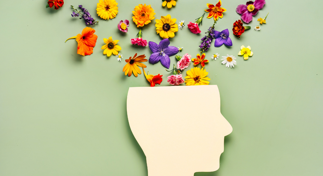 Light blue background with an outline of a head with flowers growing out the top of it