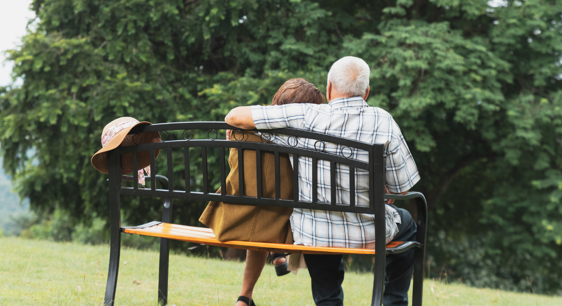 An older couple sitting on a bench outside