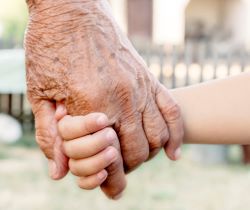 An older person holding hands with a child
