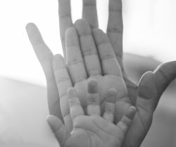 A black and white image with different size hands together