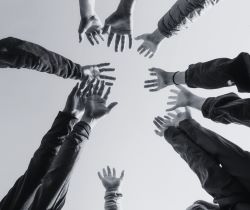 A black and white image of people's arms and hands in the sky.