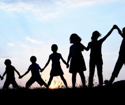 a group of children lined up playing in front of a sunset