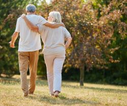 An older couple walking outside together hugging each other from the side